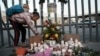 Seorang anak perempua menyalakan lilin untuk mengenang para korban kebakaran di pusat penahanan imigrasi yang menewaskan puluhan orang di Ciudad Juarez, Meksiko, Selasa, 28 Maret 2023. (AP/Christian Chavez)