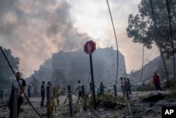Warga Palestina memeriksa puing-puing sebuah bangunan pasca terkena serangan udara Israel, di Kota Gaza, Minggu, 8 Oktober 2023. (Foto: AP)