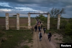 ARHIVA - Migranti iz Centralne Amerike i Kine u pratnji pripadnika Nacionalne garde Teksasa hodaju posle prelaska reke Rio Grande iz Meksika u Fronton u Teksasu, 10. aprila 2023.