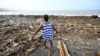 A woman looks at a beach littered with trash at Bull Bay, Jamaica, in the aftermath of Hurricane Beryl on July 4, 2024. 