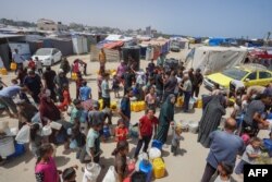 Raseljeni Palestinci čekaju u redu za vodu u kampu zapadno od Deir al-Balaha u Pojasu Gaze, 21. maja 2024. godine.
