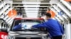 FILE - Workers are seen at the assembly line of Baojun E200 electric vehicles at a plant in Qingdao, Shandong province, China, Sept. 28, 2018. 