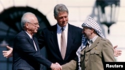 Predsednik PLO-a Jaser Arafat rukuje se sa izraelskim premijerom Jicakom Rabinom dok američki predsednik Bil Klinton stoji između njih, u Beloj kući, 13. septembra 1993. (Foto: Rojters/Gary Hershorn)