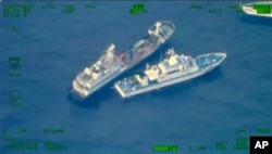 Dalam foto tambah kapal milisi China (atas) berlayar dekat kapal garda pantai Filipina BRP Cabra saat mereka mendekati beting Second Thomas Shoal di Laut China Selatan, Minggu, 22 Oktober 2023. (Foto: Angkatan Bersenjata Filipina via AP)