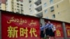 资料照：三位姑娘走过新疆莎车县街头的一幅宣传标语。（2023年7月18日）
