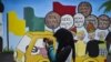 Seorang remaja perempuan tampak menggunakan ponselnya di area depan mural kampanye Pemilu 2019 yang terpasang di sebuah lokasi di Banda Aceh, pada 17 Maret 2019. (Foto: AFP/Chaider Mahyuddin)