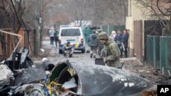 Yon solda lame Ikrenyen an enspekte debri sak sanble yon avyon yo desann nan vil Kyev peyi Ikren, Vandredi 25 Fevriye 2022. 