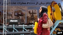  تہران میں یکم مئی 2019 کو 24ویں انٹر نیشنل آئل ، گیس ، ریفائننگ اینڈ پٹروکیمیکل نمائش میں رکھی گئی ایک مشین کےسامنے سے ایک خاتون گزر رہی ہیں : فائل فوٹو 
