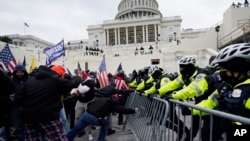 Pobunjenici lojalni predsedniku Donaldu Trampu pokušavaju da probiju policijsku barijeru oko Kapitola, 6. januara 2021. (Foto: AP/Julio Cortez, ARHIVA)
