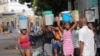 Medam pote bokit dlo nan moman gen yon rate dlo ak gaz pou kwit manje ak lot pwodwi premye nesesite apre manifestasyon popile yo te lakoz moun oblije rete lakay yo nan Potoprens, Samdi 17 Septanm, 2022. 