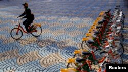 A woman rides a Youbike bicycle past a renting station outside the Taipei City Hall in Taipei, Nov. 5, 2009. 