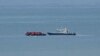 FILE - A boat thought to be carrying migrants is escorted by a vessel from the French Gendarmerie Nationale in the English Channel off Wimereux beach, France, Sept. 4, 2024. 