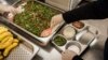 Para petugas sedang menyiapkan makanan di dapur untuk didistribusikan ke sekolah pada hari pertama pelaksanaan program makanan gratis di Jakarta, 6 Januari 2025. (Foto: Yasuyoshi CHIBA/AFP)
