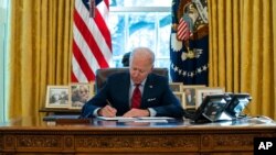 President Joe Biden signs a series of executive orders on health care, in the Oval Office of the White House, Jan. 28, 2021.