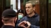 FILE - Russian opposition leader Alexey Navalny makes a heart symbol standing in a court cage in Moscow on Feb. 3, 2021. (Moscow City Court via AP)
