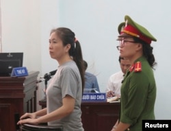 (ພາບ​ໃນ​ແຟມ) ຜູ້​ຂຽນ​ຂ່າວ​ລົງ​ໃນ​ອິ​ເຕີ​ແນັດ ຫລື blogger ທີ່​ໂດ່ງ​ດັງ, ນາງ Nguyen Ngoc Nhu Quynh (ຊ້າຍ) ຢືນ​ເພື່ອ​ໄຕ່​ສວນ​ຄະ​ດີ ຢູ່ແຂວງ Khanh Hoa, ທາງ​ພາກ​ກາງ​ຂ້ອນ​ໄປ​ທາງ​ໃຕ້​ຂອງ​ຫວຽດ​ນາມ, ວັນ​ທີ 29 ມິ​ຖຸ​ນາ, 2017. ນາງ​ຖືກ​ກ່າວ​ຫາ​ວ່າ ໃຫ້​ຂໍ້​ມູນ​ບິດ​ເບືອນ​ຕໍ່​ນະ​ໂຍ​ບາຍຂອງ​ລັດ​ຖະ​ບານ ແລະໃສ່​ຮ້າຍ​ປ້າຍ​ສີ​ພັກ​ຄອມ​ມີວ​ນິ​ສຢູ່​ໃນ​ການ​ຂຽນ​ລົງ Facebook ຂອງ​ນາງ.