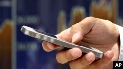 FILE - A man uses a smartphone in Tokyo, Japan, June 22, 2017. Visitors to New Zealand can now expect to be fined more than $3,000 for refusing to provide passwords to unlock electronic devices and allow customs officials to examine them under a new law condemned by civil liberties groups.