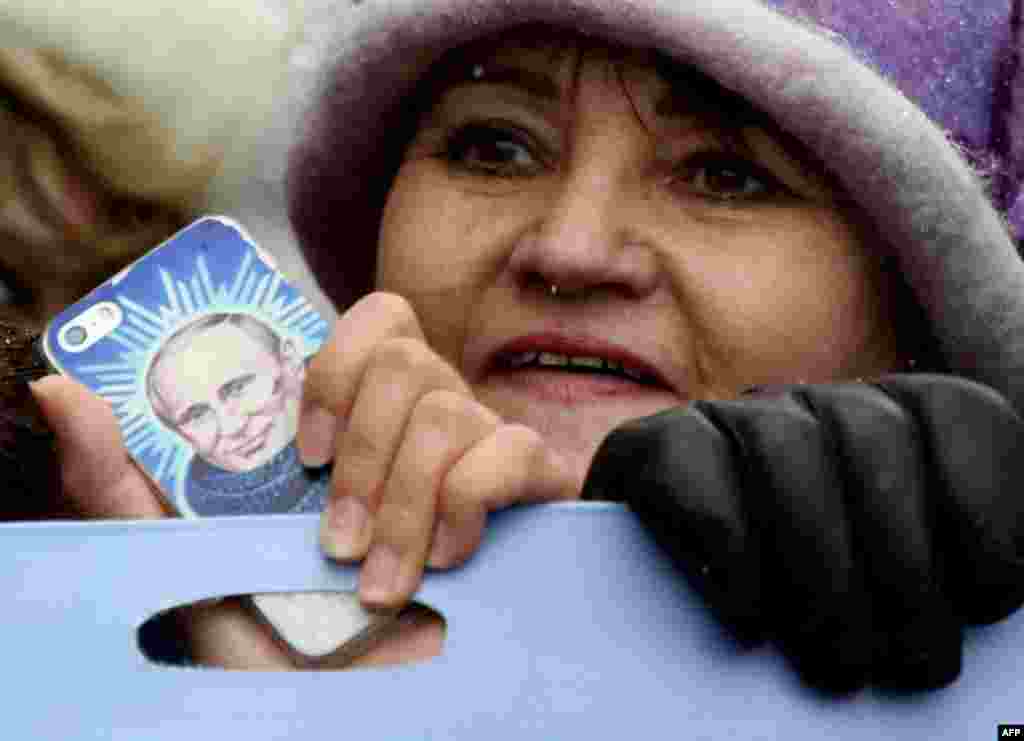A woman holds a smartphone bearing an image of Russian President Vladimir Putin as Pro-Kremlin supporters march in central Moscow as they celebrate the National Unity Day.