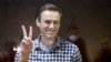 FILE - Russian opposition leader Alexey Navalny gestures as he stands in a cage in the Babuskinsky District Court in Moscow, Feb. 20, 2021.