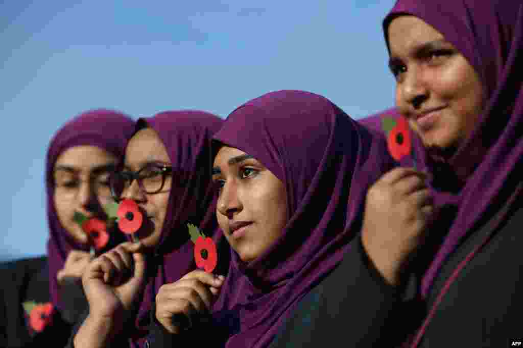 Pupils from Eden Girls' School hold poppies as they wait to observe a two minute silence in honour of Armistice Day in central London.