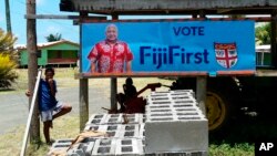 In this Nov. 7, 2018, photo, a FijiFirst poster with the image of Fiji Prime Minister Frank Bainimarama is displayed at the entrance to a village in Nausori, Fiji. 