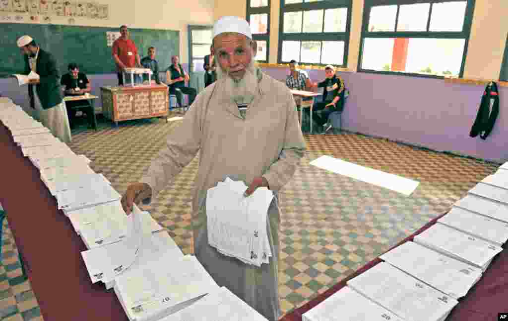 A man picks up ballots before voting in the parliamentary elections near Algiers.