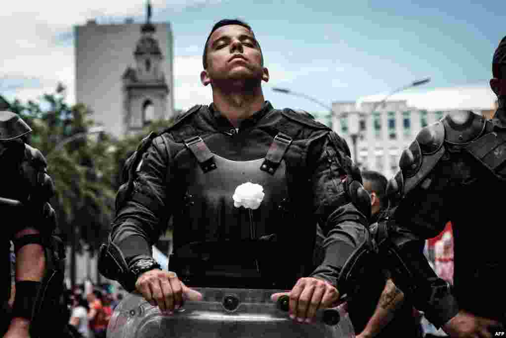 A riot police officer bearing a white flower on his bulletproof vest takes part in a public servants' protest against austerity measures in front of the Rio de Janeiro state Assembly (ALERJ) in Rio de Janeiro, Brazil, Dec. 12, 2016.