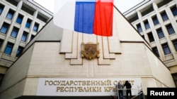 Dua pekerja memasang tanda baru bertuliskan "Dewan Negara Republik Krimea" di gedung parlemen di kota Simferopol, 19 Maret 2014. 