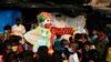 FILE - A man dressed as a clown distributes face masks to children in a slum area, amidst the coronavirus outbreak, in Mumbai, India, May 3, 2021.