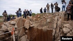 Pihak berwenang dan media lokal memeriksa poros tambang di Stilfontein, Afrika Selatan, pada 15 November 2024. Ratusan penambang ilegal diyakini bersembunyi di dalam porong tambang tersebut. (Foto: Reuters/Ihsan Haffejee)