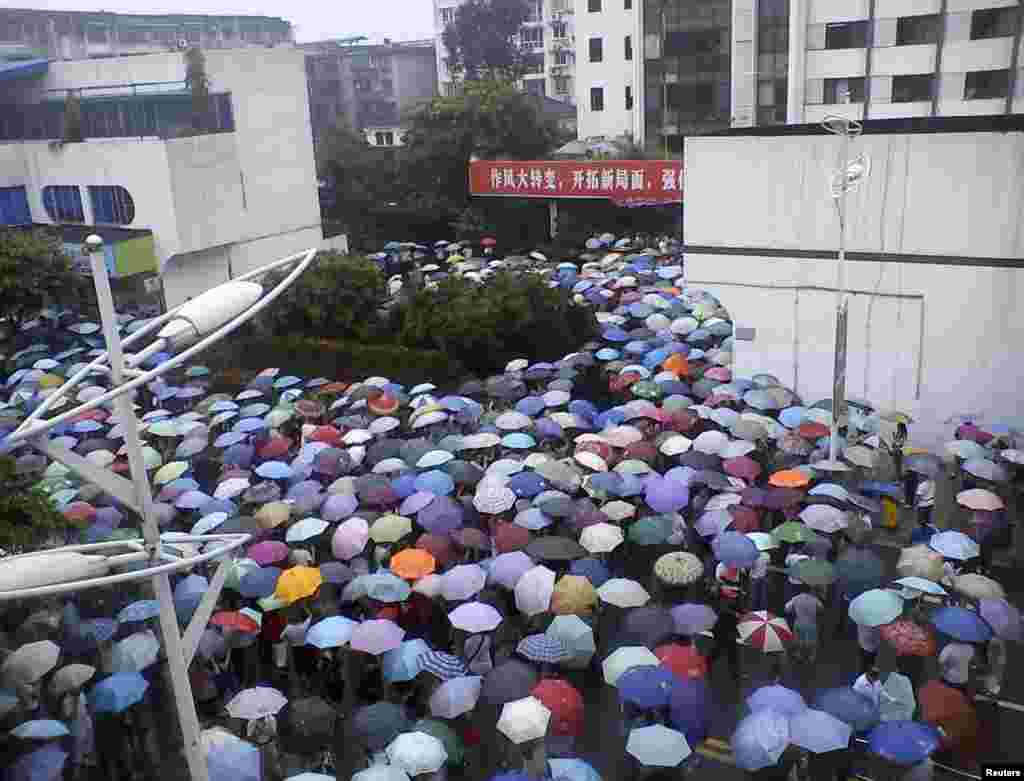 Local residents gather in front of a municipal government building in Shifang county, Sichuan province, China, in this handout picture taken July 2, 2012.
