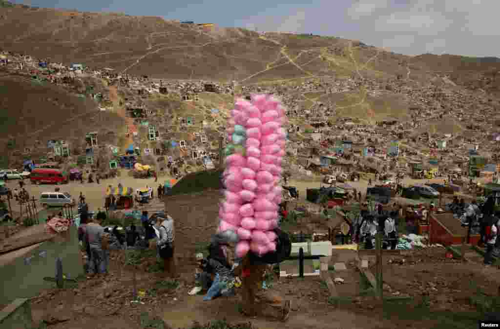 Street vendor sells candy floss as people visit tombs of relatives and friends at 'Nueva Esperanza' (New Hope) cemetery during the Day of the Dead celebrations in Villa Maria del Triunfo on the outskirts of Lima, Peru, Nov. 1, 2016.