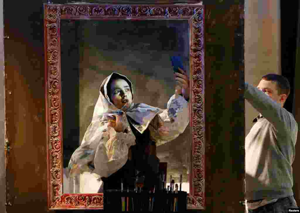 Russian artist Maria Gasanova adjusts her make-up as she finishes "The Siberian Beauty" body art work from her "The Alive Painting" series before the opening ceremony of the Cultural Universiade as part of preparation for the 2019 Winter Universiade Krasnoyarsk, in the Siberian city of Krasnoyarska.