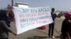 Travelers from Afghanistan hold up a sign in protest of claims that they are "economic migrants," rather than people who fled what some see as legitimate dangers before they have even applied for asylum in Athens, Greece, on April, 8, 2016. (H. Murdock / 