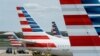 FILE - A member of a ground crew walks past American Airlines planes parked at the gate during the coronavirus outbreak at Ronald Reagan National Airport in Washington, April 5, 2020.
