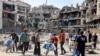 People walk past rubble and damaged buildings in the Tuffah district east of Gaza City on July 8, 2024 amid the ongoing conflict in the Palestinian territory between Israel and Hamas.