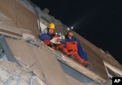 FILE - Rescue workers carry a baby swaddled in a cloth from the rubble of a toppled building after an earthquake in Tainan, Taiwan, Feb. 6, 2016.