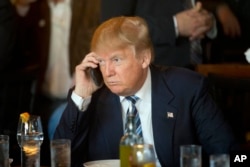 FILE - Then-Republican presidential candidate Donald Trump listens to his mobile phone during a lunch stop in North Charleston, S.C., Feb. 18, 2016. Trump’s approach to Twitter has been as unorthodox as his presidential campaign.
