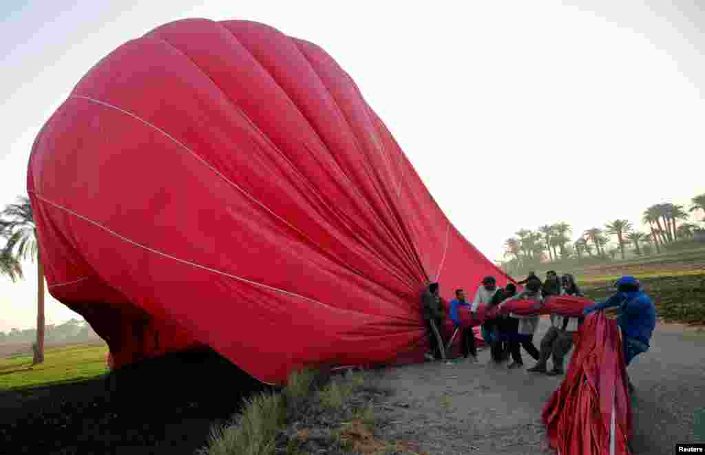 Crew members work to secure a hot-air balloon after landing at the city of Luxor, south of Cairo, Egypt.