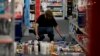 A man picks up fallen goods at a CVS store after an earthquake, March 28, 2014, in La Mirada, California.