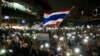 ผู้ชุมนุมรายหนึ่งโบกธงชาติไทย และถือป้ายข้อความ ขณะร่วมประท้วงเมื่อวันที่ 18 ตุลาคม 2020 ที่กรุงเทพมหานคร (ที่มา: เอพี)