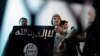 Seorang militan Al-Qaeda Yaman (tengah) menunjukkan spanduk saat persidangan terkait keamanan negara di Sanaa, Yaman, 23 April 2013. (Foto: Hani Mohammed/AP Photo)