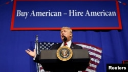 Arhiva - Novoizabrani predsednik Donald Tramp, tada predsednik, govori u Kenoši, Viskonsin, 18. aprila 2017, ispred parole "Kupujmo američko, unajmljujmo Amerikance".