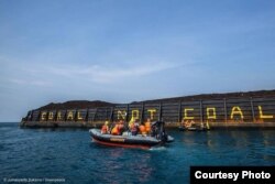 Aktivis Greenpeace menulis Coral not Coal di lambung tongkang batubara di Karimunjawa. (Foto: Greenpeace Indonesia)