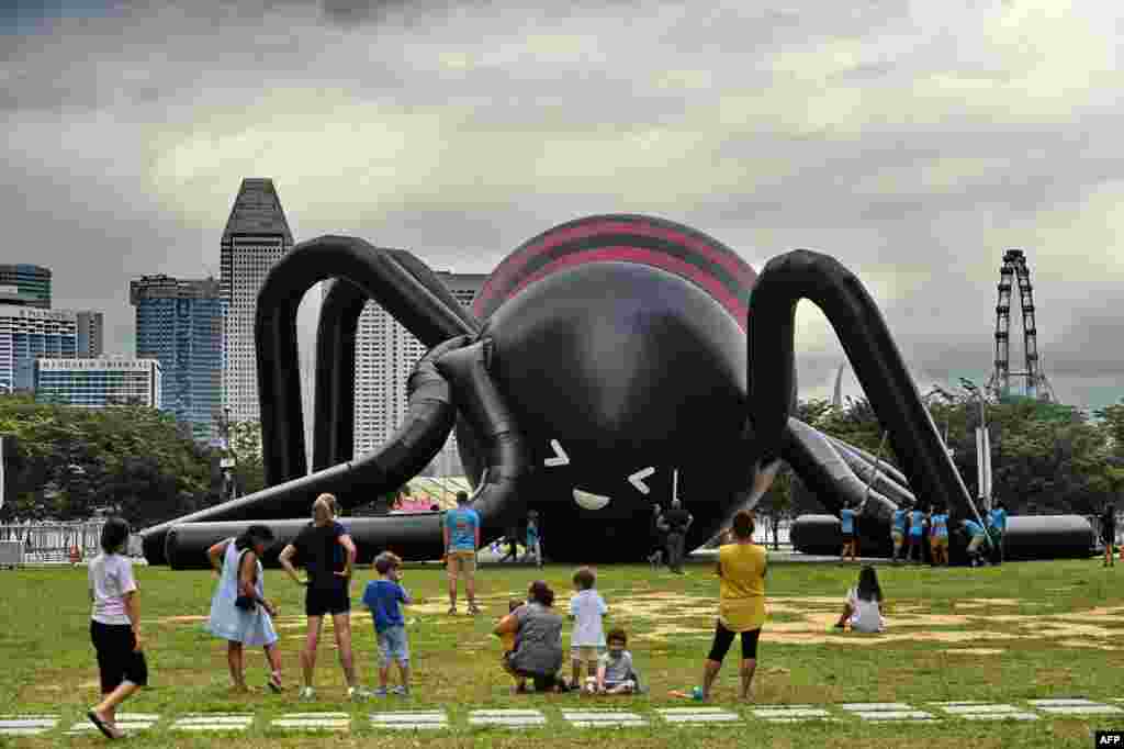 People watch as workers inflate a near-10 meter-high giant spider by Singaporean artist Jackson Tan in Singapore’s Marina Bay financial district.