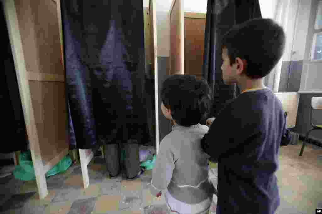 Boys wait outside a voting booth for their father during parliamentary elections at a polling station in Boumerdes, east of Algiers. 