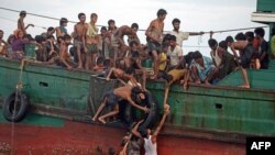 Rohingya migrants pass food supplies dropped by a Thai army helicopter to others aboard a boat drifting in Thai waters off the southern island of Koh Lipe in the Andaman sea on May 14, 2015. 