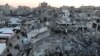 Palestinians walk among the rubble of buildings, In Khan Younis
