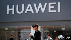 People walk past a Huawei retail store in Beijing, Sunday, June 30, 2019. Once again, Presidents Donald Trump and Xi Jinping have hit the reset button in trade talks between the world's two biggest economies, at least delaying an escalation in…