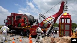 Para anggota tim evakuasi mengangkat kurungan yang digunakan untuk menyelamatkan penambang yang terperangkap di sebuah tambang emas yang telah ditinggalkan di Stilfontein, Afrika Selatan, pada 16 Januari 2025. (Foto: AP/Themba Hadebe)